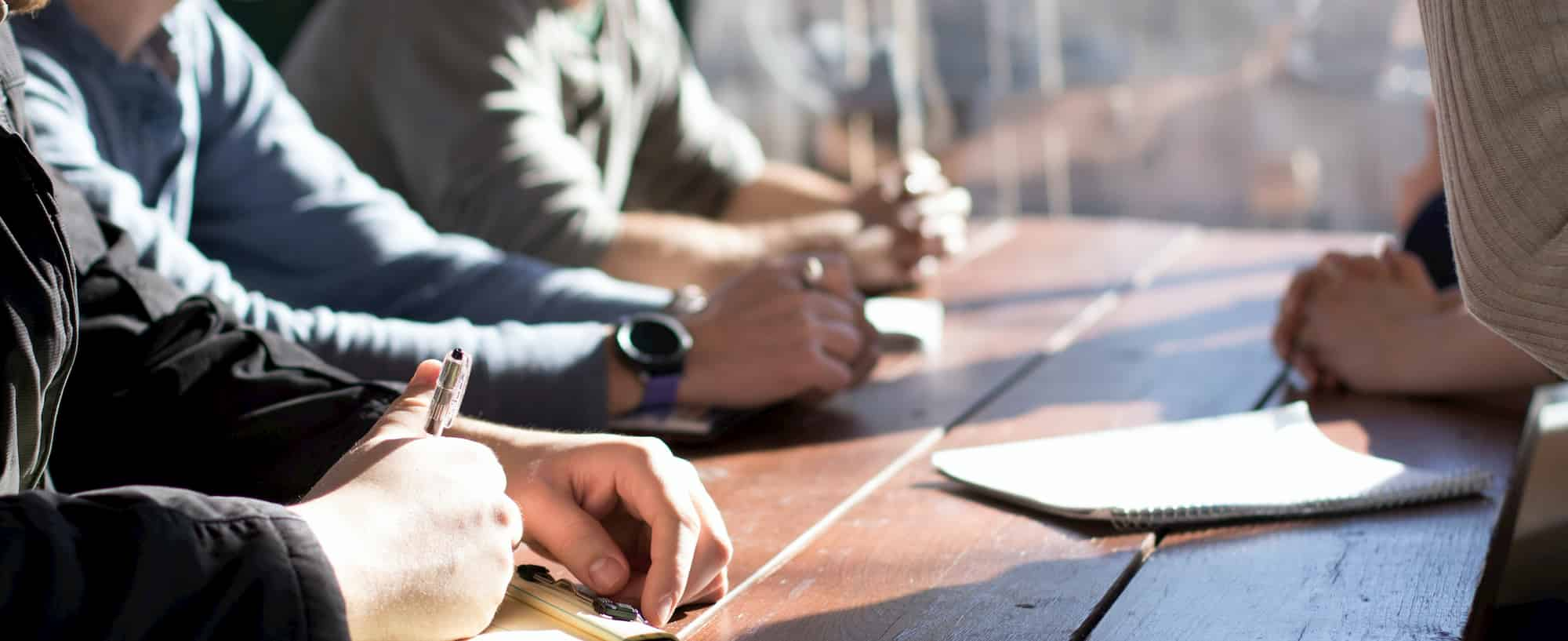 Meeting of people with notepads at a bench outdoors