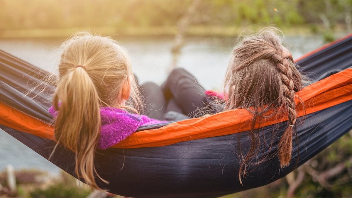 Two girls in a hammock by a lake to illustrate Mackman Research's work with Sure Start Hyndburn